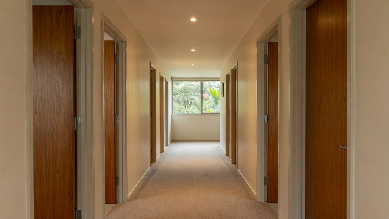A carpeted apartment corridor lined with timber apartment entry doors
