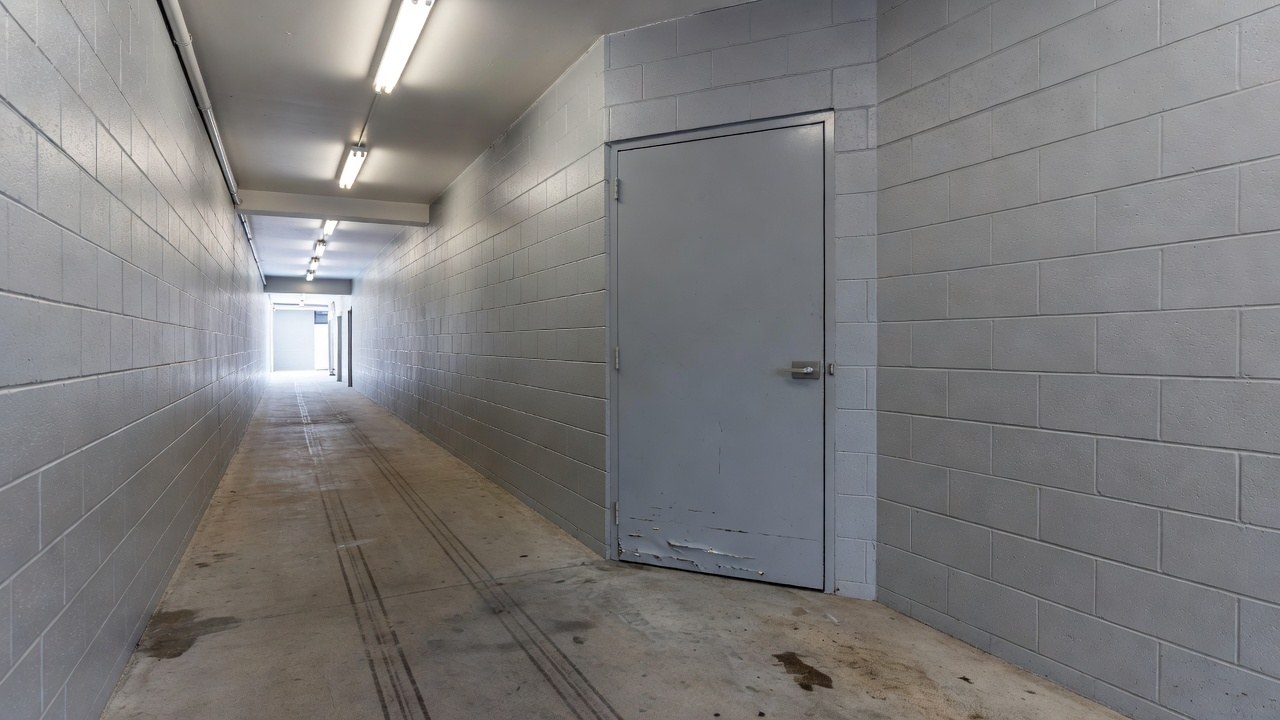 A painted fire door in a service corridor with a dented lower edge