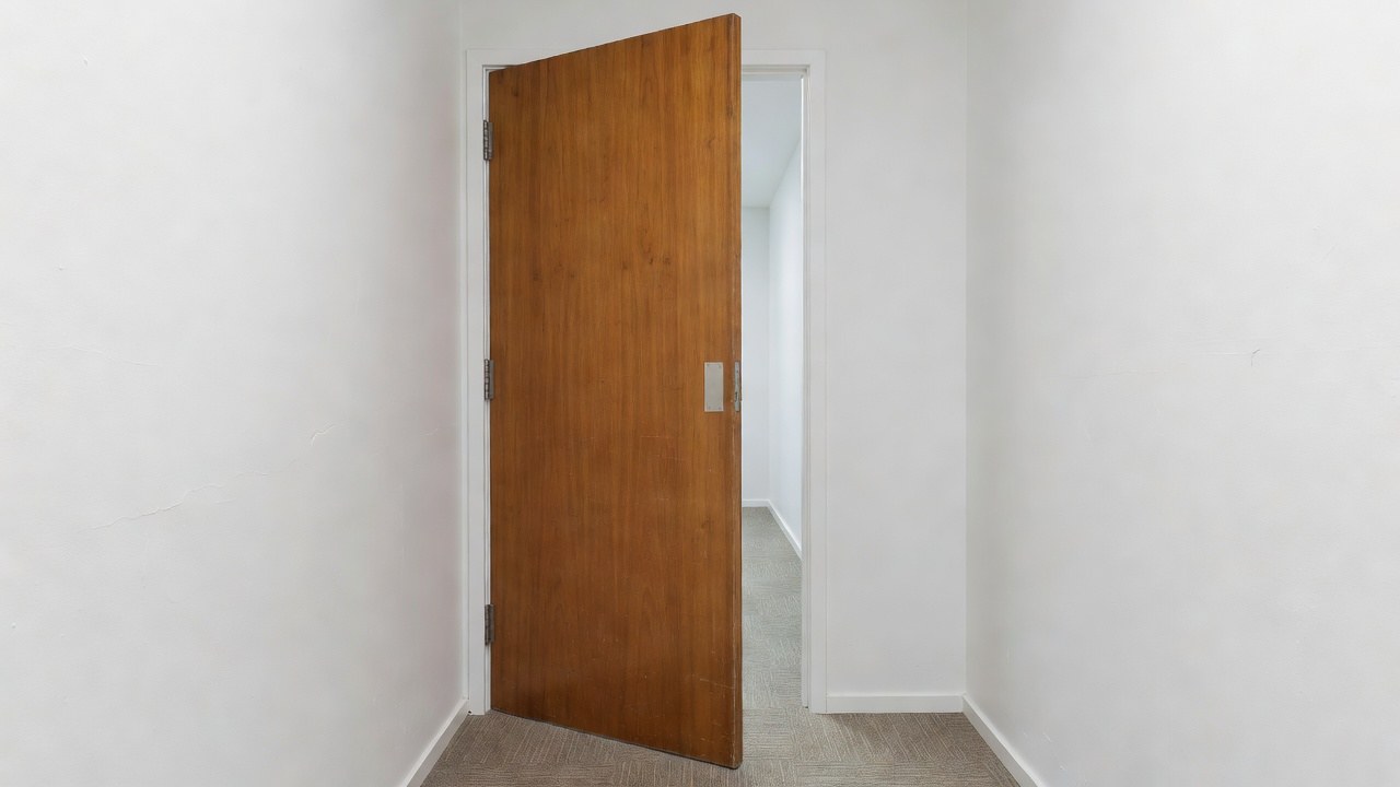 A timber fire door standing open, showing its hinge edge and hinges