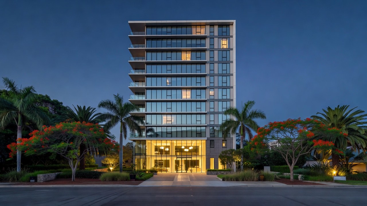 A modern Brisbane apartment building at dusk with a lit glass lobby