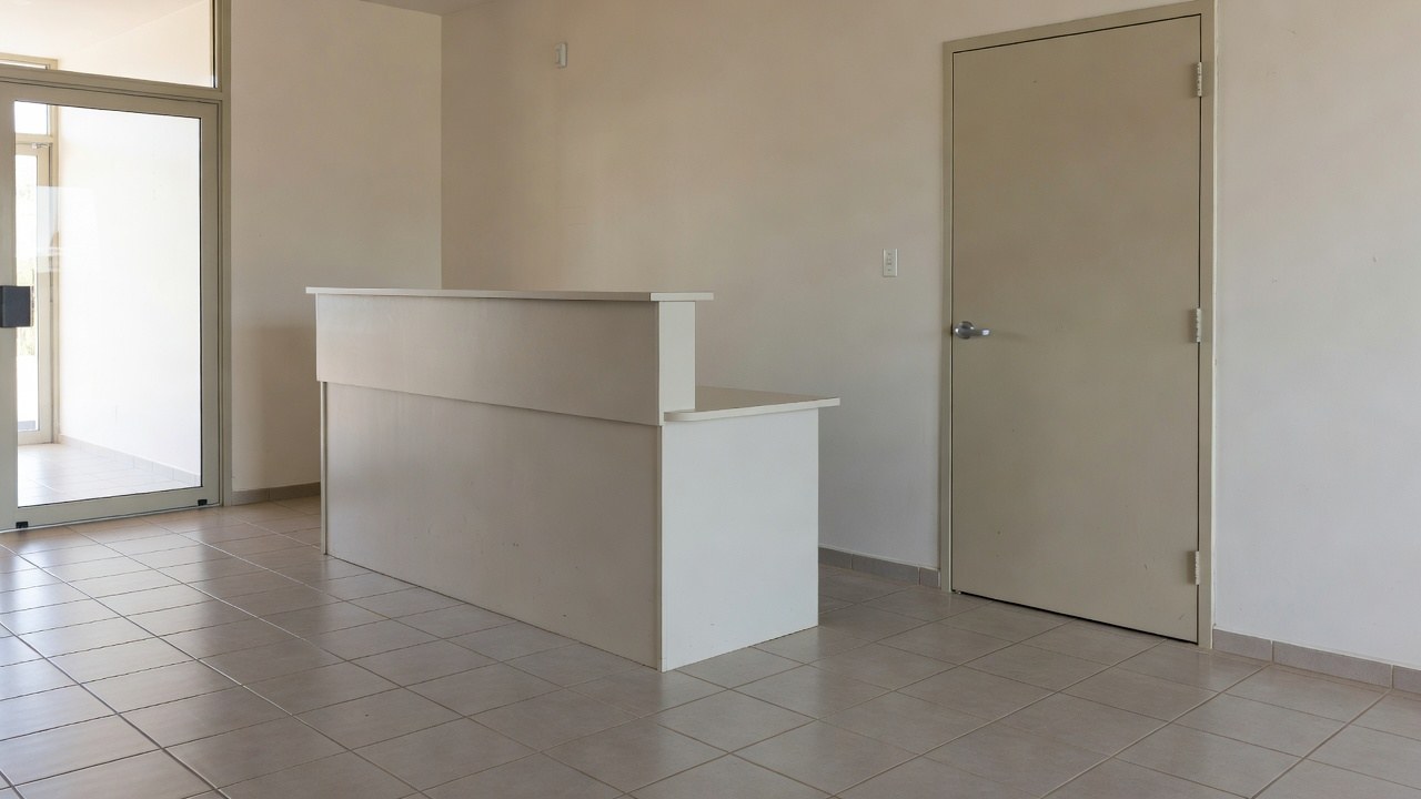A small office building entry lobby with a reception counter and a stair door